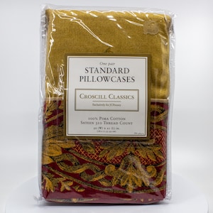 May include: A packaged set of two standard pillowcases. The top portion is a solid mustard yellow, while the bottom features a burgundy pattern with gold floral accents. The label reads "Croscill Classics" and "100% Pima Cotton". Each pillowcase measures 30 x 21 inches.