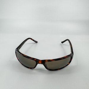 May include: Rectangular sunglasses with a tortoiseshell pattern frame and tinted lenses. The sunglasses have a classic design, suitable for various face shapes. The lenses appear to be a shade of brown, offering protection from the sun.