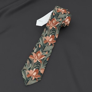 May include: A necktie featuring a dark green background with a repeating pattern of orange-toned flowers and light green foliage. The tie has a pointed tip and a white fabric lining visible at the top, showcasing a detailed botanical print design.