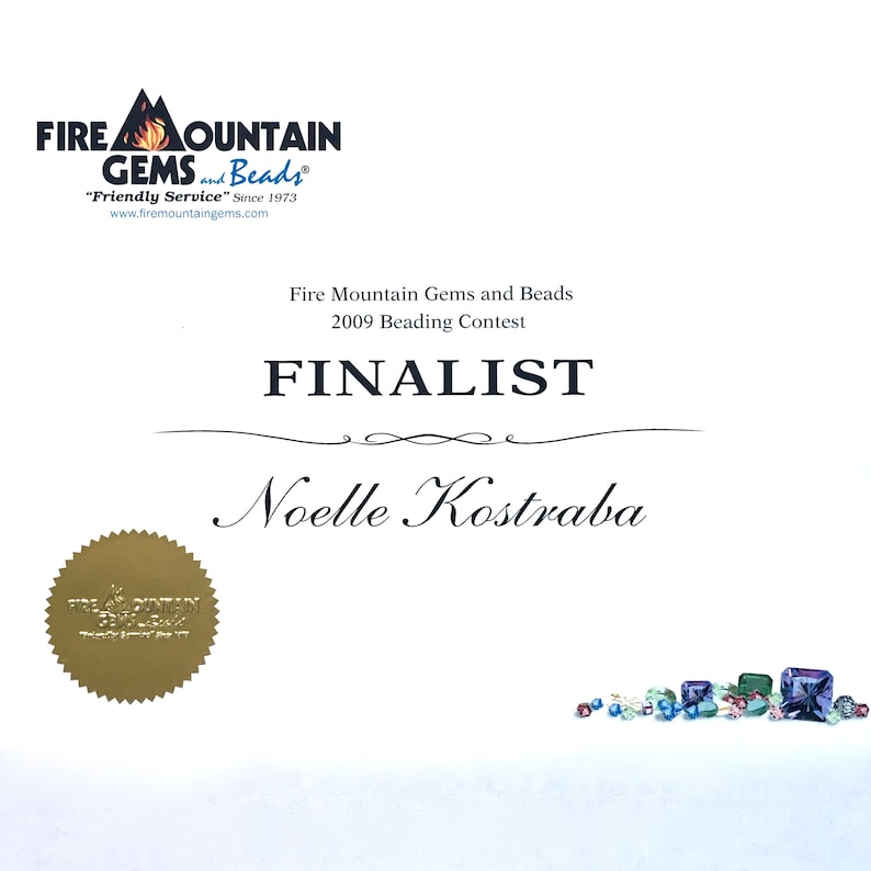 Op de afbeelding: Een certificaat van Fire Mountain Gems and Beads, met de tekst "FINALIST" en de naam "Noelle Kostraba". Het certificaat bevat het bedrijfslogo en details over de kralenwedstrijd van 2009. Er is ook een gouden zegel aanwezig.