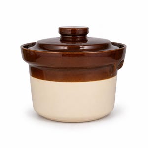 May include: A two-toned ceramic crock with a glossy dark brown glazed lid and upper rim, transitioning to a matte cream-colored base. The cylindrical vessel features a wide opening, a fitted lid with a central knob, and small side handles.
