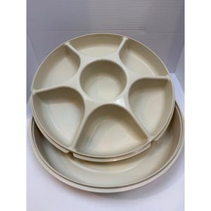 May include: Two-piece beige serving platter set. The top platter has six pie-shaped compartments around a central circle. The bottom platter is a solid, shallow dish. The set is made of a durable plastic material.