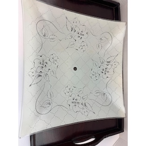 May include: A square, frosted glass light fixture cover featuring a delicate black line-drawn floral pattern and a subtle diamond lattice background. The center of the glass panel has a small circular opening for mounting hardware.