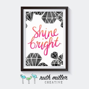 May include: A framed print with a white background and black geometric shapes. The text "Shine bright" is written in pink and orange watercolor lettering.