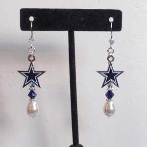 May include: A pair of silver dangle earrings featuring a blue and white star charm with a pearl and crystal accents.