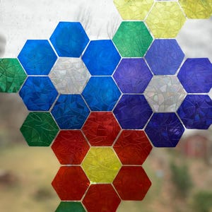 Op de afbeelding: Een kleurrijk honingraatontwerp gemaakt van zeshoekige stickers. De stickers zijn in tinten blauw, groen, paars, rood en geel. De stickers zijn gerangschikt in een patroon dat lijkt op een honingraat.