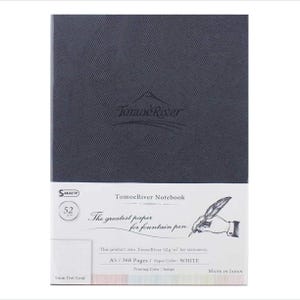 Op de afbeelding: Een donkergrijs notitieboek met het Tomoe River logo en de tekst "Tomoe River Notebook" gedrukt op de voorzijde. De tekst "The greatest paper for fountain pen" is gedrukt onder het logo. Het notitieboek is gemaakt in Japan en heeft 368 pagina's van 52 g/m² wit papier.