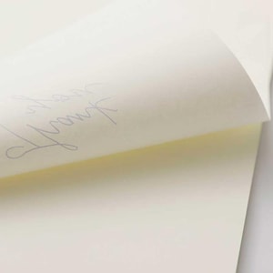 May include: A close-up of a blank, off-white notepad with a handwritten inscription that says "From the"