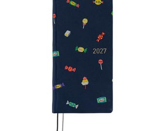 May include: A dark blue planner with the year 2027 printed in gold on the front cover. The cover features a repeating pattern of colorful candy illustrations, including lollipops, wrapped hard candies, and gummies. Two thin bookmarks hang below.