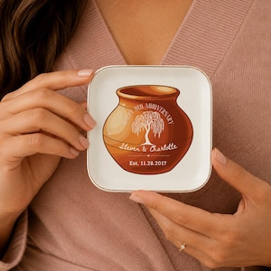 May include: A square white ceramic trinket dish with a gold-toned rim. The center features a brown pottery jar illustration with a white willow tree graphic and text reading Happy 9th Anniversary, Steven & Charlotte, Est. 11.28.2017.