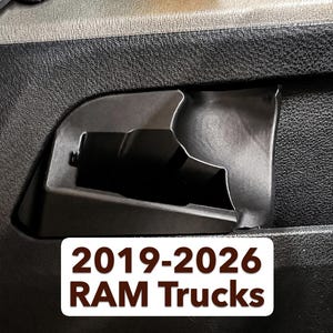 May include: Black interior door handle pocket for 2019-2026 RAM Trucks. The pocket is molded into the door panel and has a textured surface. The text "2019-2026 RAM Trucks" is displayed on a white rectangle.