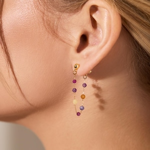 May include: Gold clip-on earrings with a chain of colourful beads. The beads are purple, red, yellow, and orange.