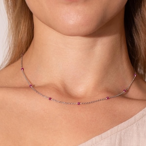 May include: A delicate silver chain necklace with small pink gemstones.
