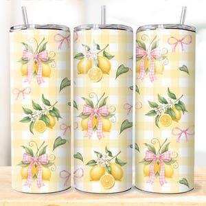 Puede incluir: Tres vasos de acero inoxidable con un patrón de cuadros amarillos y blancos. Cada vaso presenta un diseño de acuarela de limones, hojas verdes y lazos rosas. Los vasos tienen una pajita transparente.