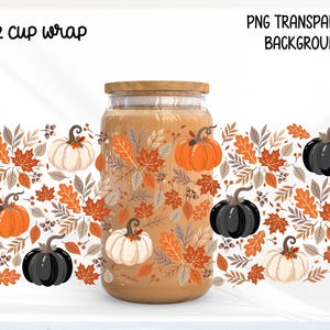 May include: A 16 oz cup wrap design featuring a pattern of orange, white, and black pumpkins interspersed with autumn leaves and acorns. The text 16 oz cup wrap and PNG TRANSPARENT BACKGROUND is visible. The design is displayed on a glass jar.