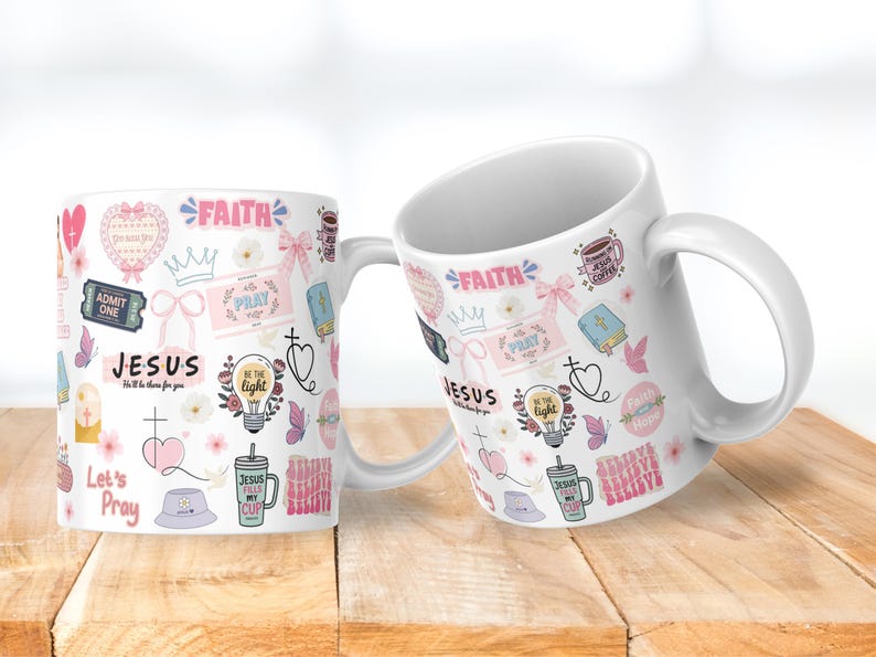 May include: Two white ceramic mugs with a variety of pink and light blue graphics. The mugs feature the words "Faith", "Jesus", and "Pray", along with other religious symbols and phrases. The mugs are on a wooden surface.