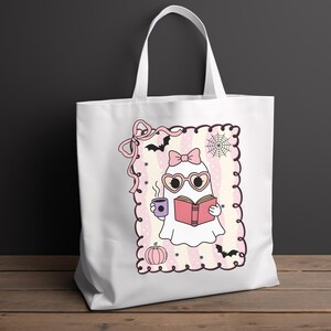 May include: White tote bag featuring a cartoon ghost reading a book and holding a coffee cup. The ghost wears heart-shaped glasses and a bow. The design includes bats, a spiderweb, and a pumpkin, all in pink and purple.