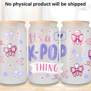 Puede incluir: Tres vasos de vidrio esmerilado con tapas y pajitas de bambú. Cada vaso está decorado con lazos rosas y morados, estrellas y la frase "It's a K-POP THING". Los vasos están diseñados para bebidas frías.