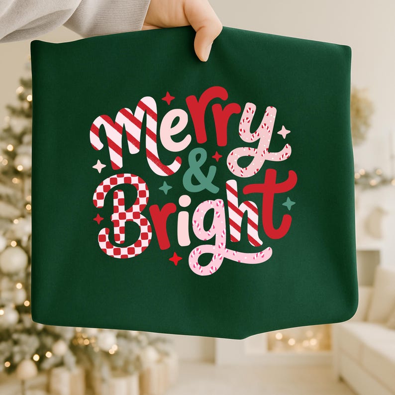 以下が含まれることがあります： 「Merry & Bright」の文字がデザインされた、お祝いの雰囲気の濃い緑色の正方形の布。 赤、白、ピンクの色と星のアクセントが特徴で、ホリデーデコレーションに最適です。 布は人の手で持たれています。