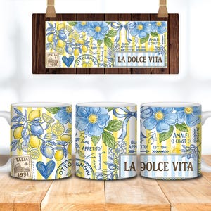 May include: Three white ceramic mugs with a design featuring lemons, blue flowers, and the text "LA DOLCE VITA." The design includes the words "ITALIA" and "AMALFI COAST." The mugs are on a wooden surface.