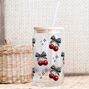 Peut inclure: Un gobelet en verre transparent en forme de canette avec un couvercle en bambou et une paille transparente. Le gobelet est d&eacute;cor&eacute; de cerises rouges, de n&oelig;uds &agrave; carreaux noirs et blancs et de petites &eacute;toiles. Le motif est r&eacute;p&eacute;t&eacute; sur le verre.