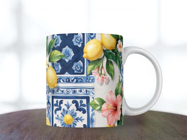 May include: White ceramic mug featuring a vibrant design of lemons, pink flowers, and green leaves against a backdrop of blue and white tiles. The mug has a curved handle and is suitable for hot or cold beverages.