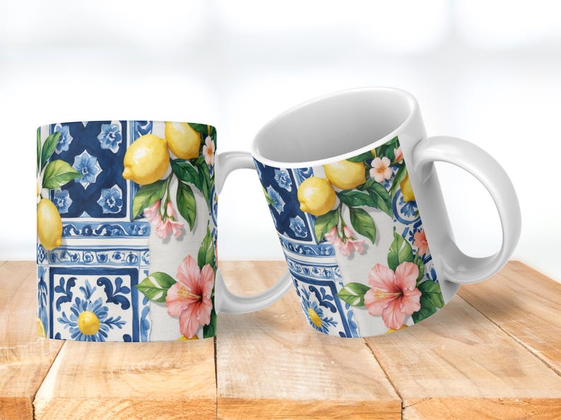 May include: Two white ceramic mugs with a vibrant design featuring lemons, pink flowers, and blue tile patterns. The mugs have a classic handle and are set against a wooden surface, showcasing a bright and cheerful aesthetic.