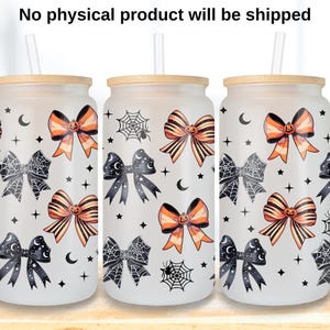 Op de afbeelding: Drie glazen bekers in de vorm van een blikje met bamboe deksels en rietjes. De bekers zijn versierd met oranje en zwarte strikken, spinnenwebben, manen en sterren. De tekst "No physical product will be shipped" staat bovenaan.