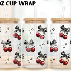 Peut inclure: Gobelet en verre transparent avec un couvercle en bois et une paille. Le gobelet est d&eacute;cor&eacute; d'un motif de cerises rouges et de n&oelig;uds &agrave; carreaux noirs et blancs. Le texte "16 OZ CUP WRAP" est en haut.