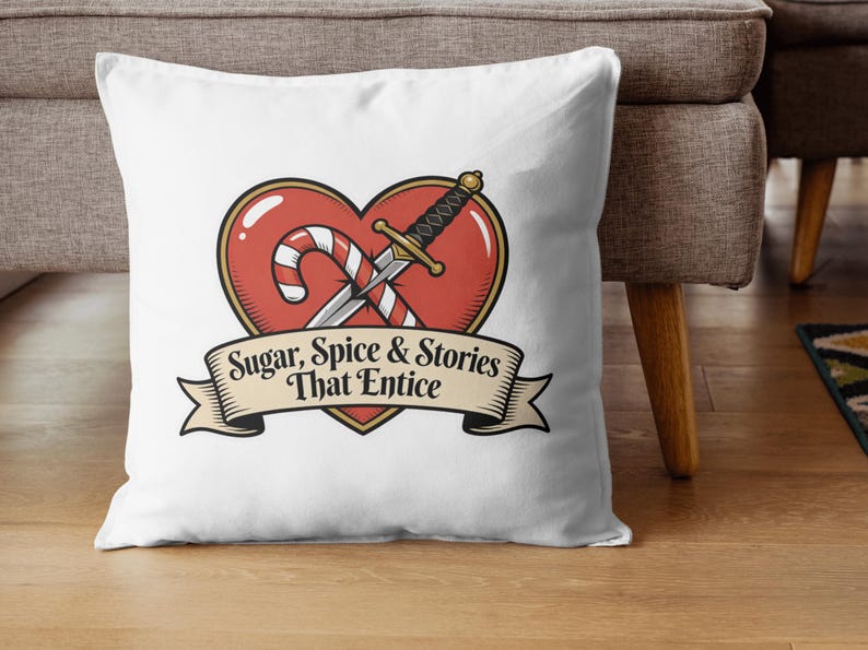 May include: White throw pillow with a heart-shaped design featuring a candy cane, sword, and banner. The banner reads "Sugar, Spice & Stories That Entice". The design has red, gold, and black accents. The pillow is on a wooden surface.