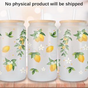 Pode incluir: Três copos de vidro fosco com um design de limão e flores. Os copos têm tampas de bambu e canudos transparentes.