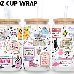 May include: Three clear 16 oz glass cups with bamboo lids and straws, featuring a colorful wrap design with various illustrations and text including 'not my problem', 'I care not found', 'Your opinion has been declined', and 'I gladly will'.