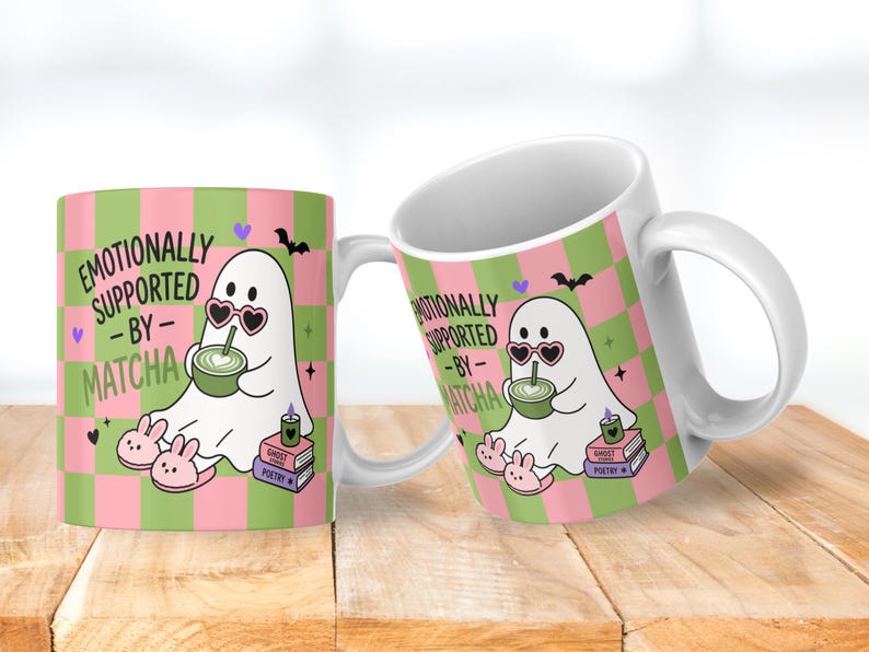 May include: A white ceramic mug featuring a pink and green checkered pattern. The design shows a white ghost wearing heart-shaped sunglasses and bunny slippers, holding a green matcha drink. Text reads: EMOTIONALLY SUPPORTED BY MATCHA.