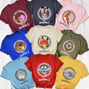May include: A collection of colorful t-shirts featuring characters from the movie "Zootopia 2." Each shirt displays a different character within a checkered circle, with the movie title below. Colors include red, blue, pink, and yellow.