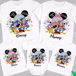 May include: White family matching t-shirts and a onesie featuring a colorful Disney graphic. The shirts have the words "Daddy", "Mommy", "Sister", and "Brother" printed on them. The onesie says "Brown's". All shirts have "Disney Trip 2026" text.
