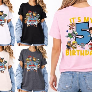 May include: A collection of five short-sleeved t-shirts in white, black, light pink, beige, and dark gray. The shirts feature Paw Patrol character graphics with text including Mama, Dad, Aunt, Sister of the Birthday Boy, and It's My 5th Birthday.