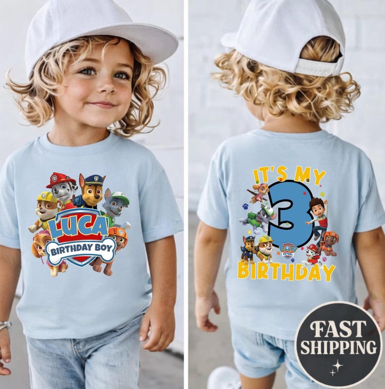 May include: A light blue t-shirt featuring Paw Patrol characters. The front displays the text 'LUCA BIRTHDAY BOY' with a shield graphic. The back shows a large blue number '3' with the text 'IT'S MY BIRTHDAY' and additional character graphics.