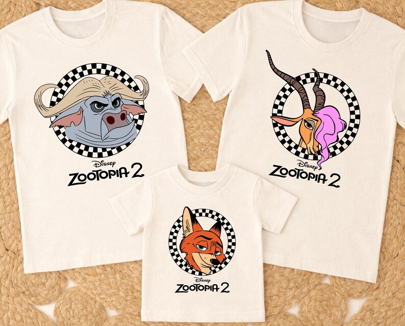 May include: Three white t-shirts with cartoon character graphics from Disney's Zootopia 2. Each shirt features a different character in a black and white checkered circle. The text "Zootopia 2" is printed below each graphic.