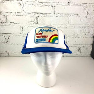 Könnte beinhalten: Weiß-blaue Trucker-Cap mit blauem Schirm und Mesh-Rücken. Die Kappe hat einen Aufnäher mit dem Wort "Rainbow" über "Farm Computer Digital" und einer Regenbogen-Grafik.