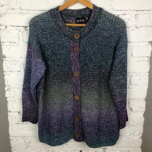 May include: A long-sleeved, ombre cardigan with a button-up front. The cardigan is a mix of purple, blue, and green colors. The cardigan has a tag that says "g+g XL".