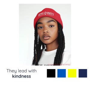 May include: A person wearing a red knitted beanie with the words "LOVE & UNITY" in white. The person is also wearing a white t-shirt. The image includes the text "They lead with kindness" and a colour palette.