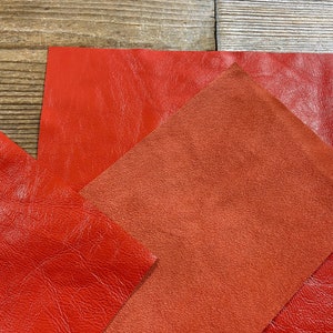 May include: Three pieces of leather in different shades of red. The leather is smooth and textured.
