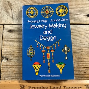 May include: A blue book titled "Jewelry Making and Design" by Augustus F. Rose and Antonio Cirino. The cover features gold and red jewelry illustrations. The book has over 325 illustrations.