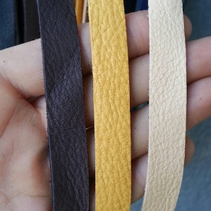 May include: Three leather strips in different colors: dark brown, yellow, and cream. The strips are smooth and have a textured surface.