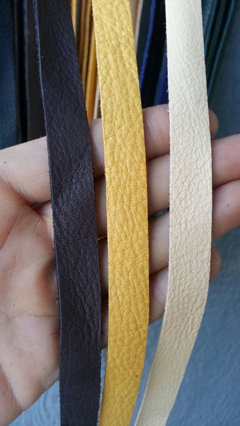 May include: Three leather strips in different colors: dark brown, yellow, and cream. The strips are smooth and have a textured surface.