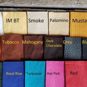 May include: A selection of leather swatches in various colours, including white, rust, tobacco, mahogany, dark chocolate, grey, black, forest green, royal blue, turquoise, hot pink, and red. The swatches are arranged in three rows.