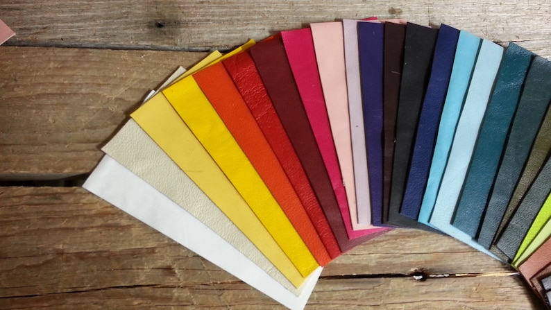 May include: A fan-shaped arrangement of leather swatches in various colors, including white, yellow, orange, red, pink, purple, blue, green, and brown.