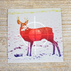 May include: A stylized image of a deer with antlers in a crosshairs target. The deer is depicted in a gradient of red, orange, yellow, and purple.