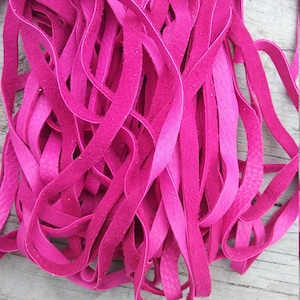 May include: A pile of bright pink leather cord, approximately 6 mm wide, for crafting projects.