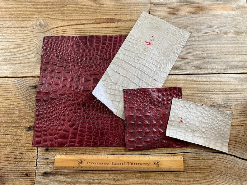 May include: Four pieces of leather, two are burgundy with a crocodile pattern and two are white with a crocodile pattern. A wooden ruler with the text "Promise Land Tannery" is in the bottom center of the image.